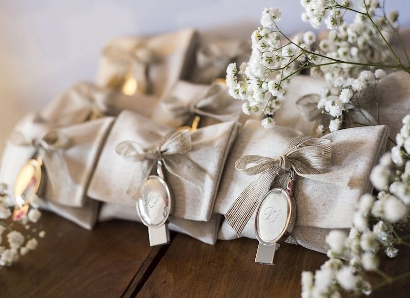 Eleganti bomboniere di matrimonio confezionate in tessuto con fiocco e ciondolo personalizzato